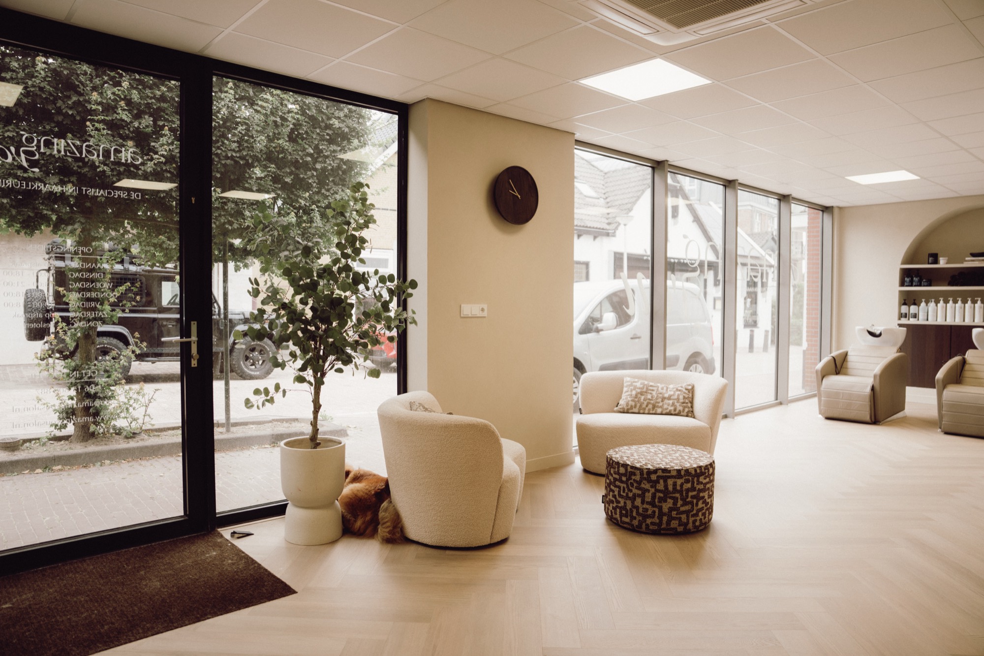 De lichte lounge van de salon met fauteuils en grote ramen